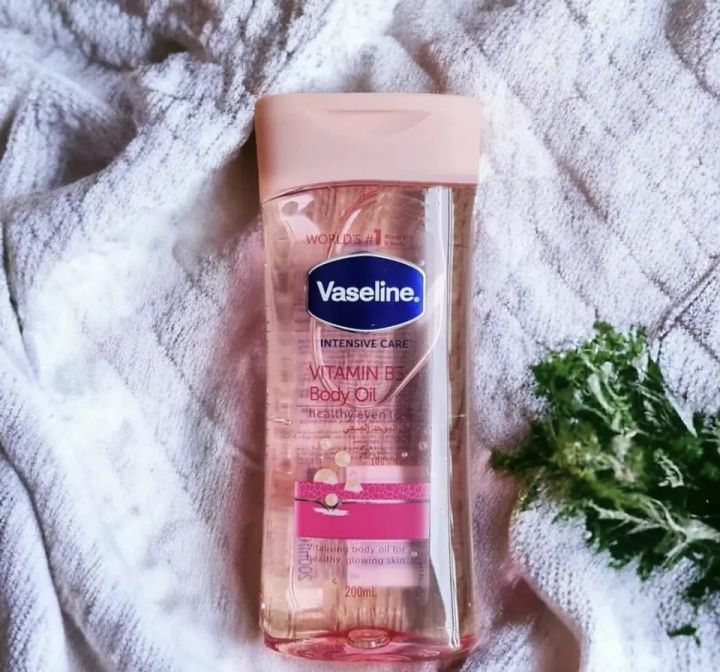 Vaseline lotion bottle on a white textured cloth next to green leafy sprigs.
