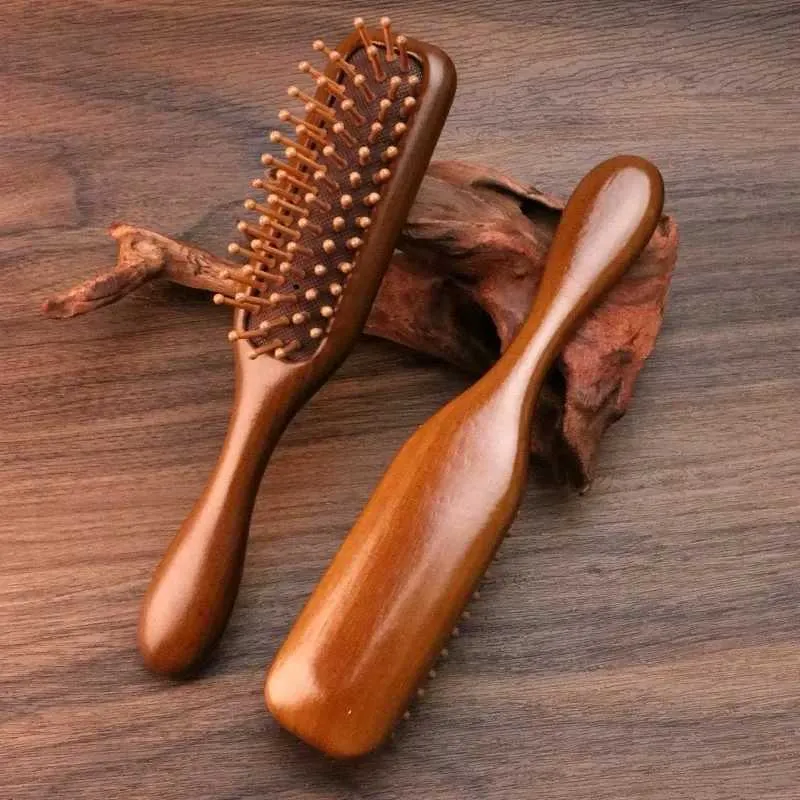 Two wooden hairbrushes with rounded bristles on a wooden surface.