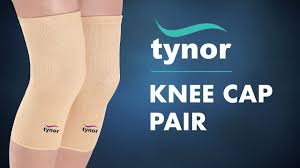 Beige knee cap supports worn on both legs with Tynor logo, on a dark blue background.