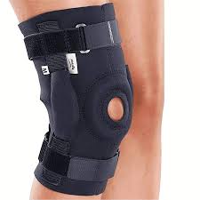 Black knee brace with straps and open patella worn on a person's leg.