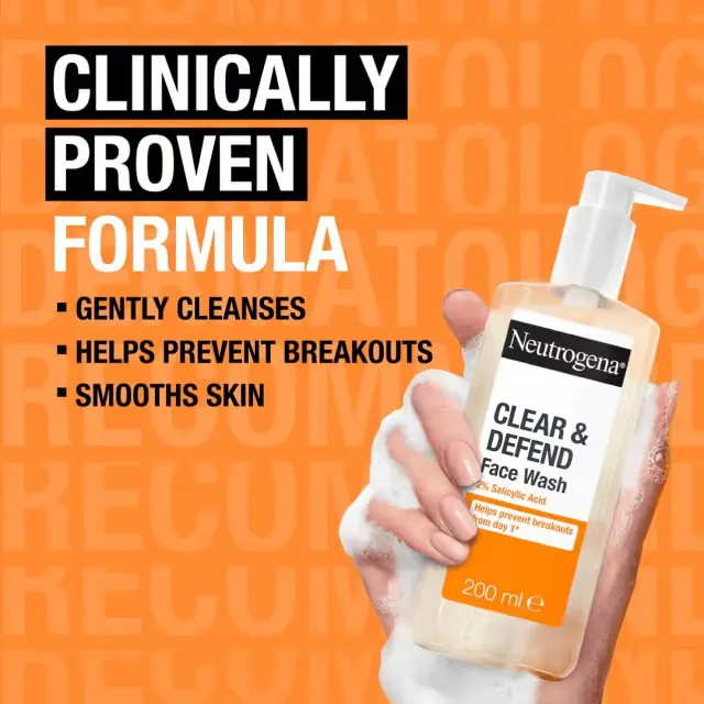 Hand holding Neutrogena Clear & Defend Face Wash bottle against orange background.