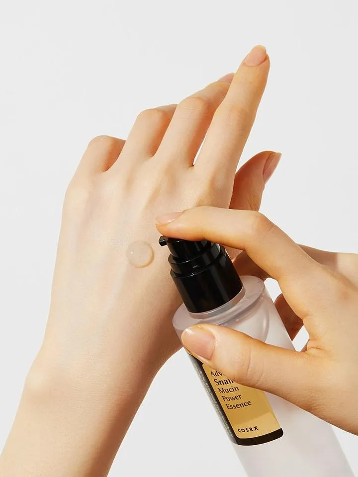 A person dispensing serum onto the back of their hand against a light background.