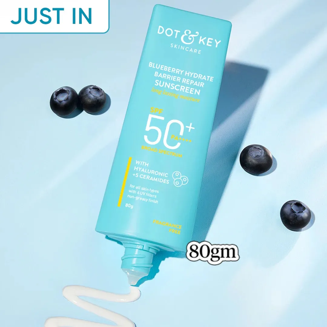 Blue tube of Dot & Key sunscreen with blueberries and sunscreen cream on a light blue background.
