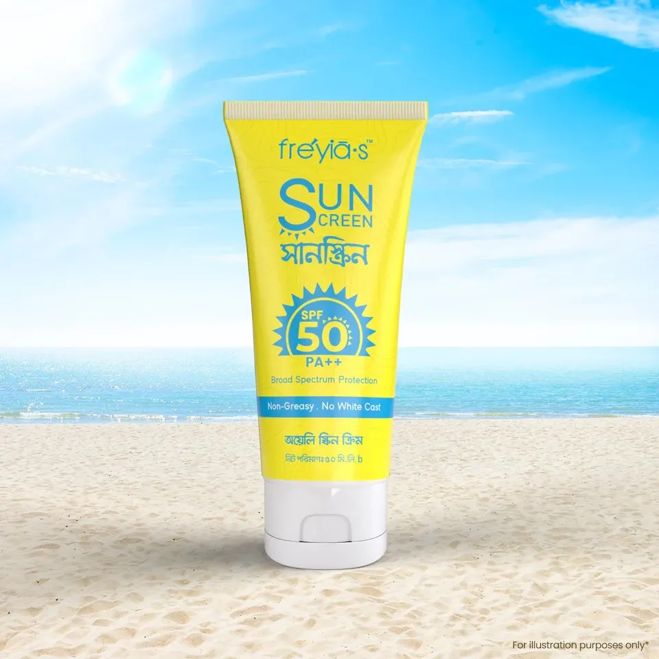 Yellow sunscreen tube with SPF 50 on sandy beach, blue sky and ocean in background.