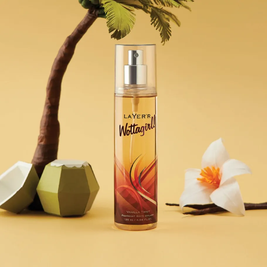 Perfume spray bottle with tropical design, beside a palm tree, coconut, and white flower.