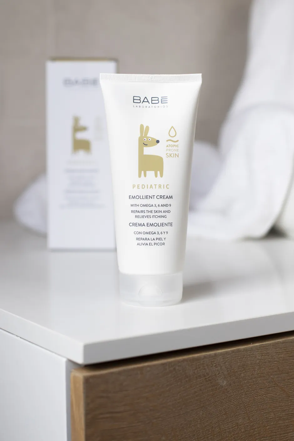 White skincare product tube with gold animal design on a white nightstand.
