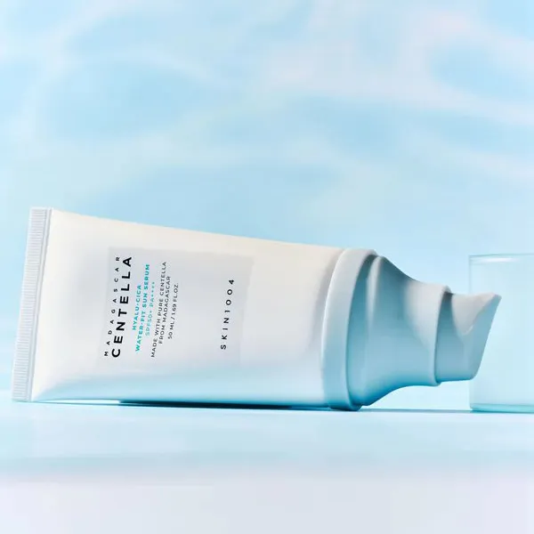 White skincare cream tube with blue label lying on a light blue background.