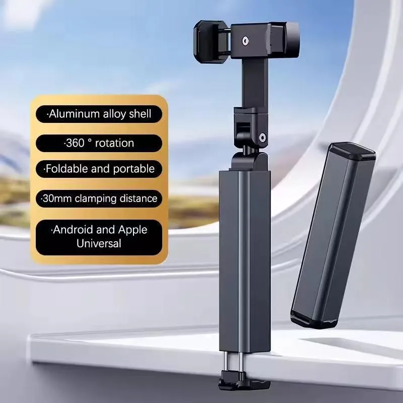 Black foldable phone holder with rotating head on a table next to a window, sleek design.