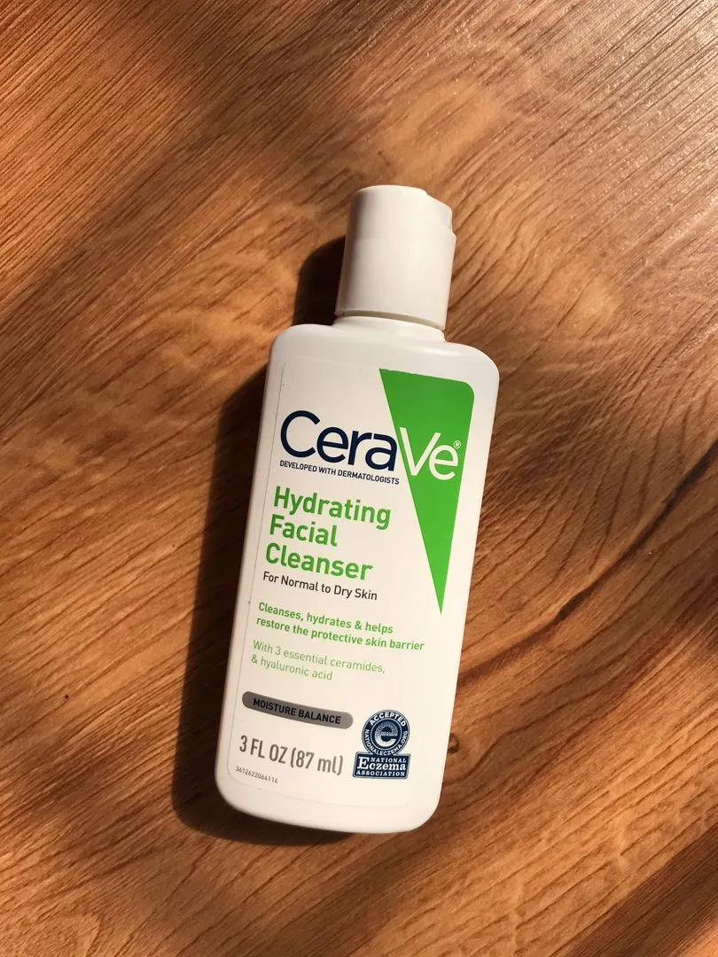 CeraVe Hydrating Facial Cleanser bottle on a wooden surface.