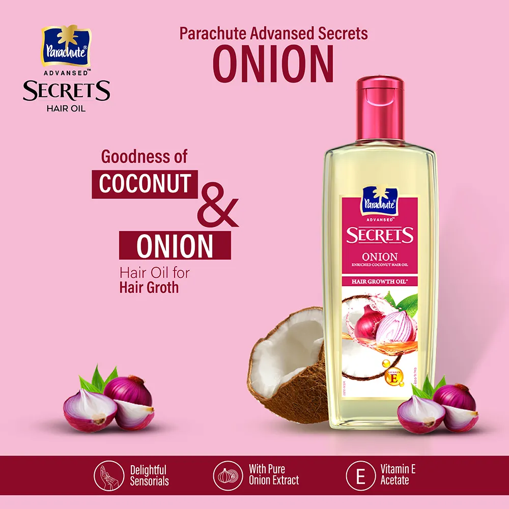 Hair oil bottle with coconut and onions on a pink background, emphasizing hair growth benefits.