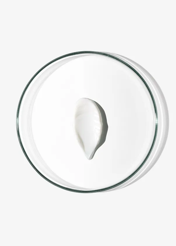 White cream dollop on a clear glass dish against a plain background.