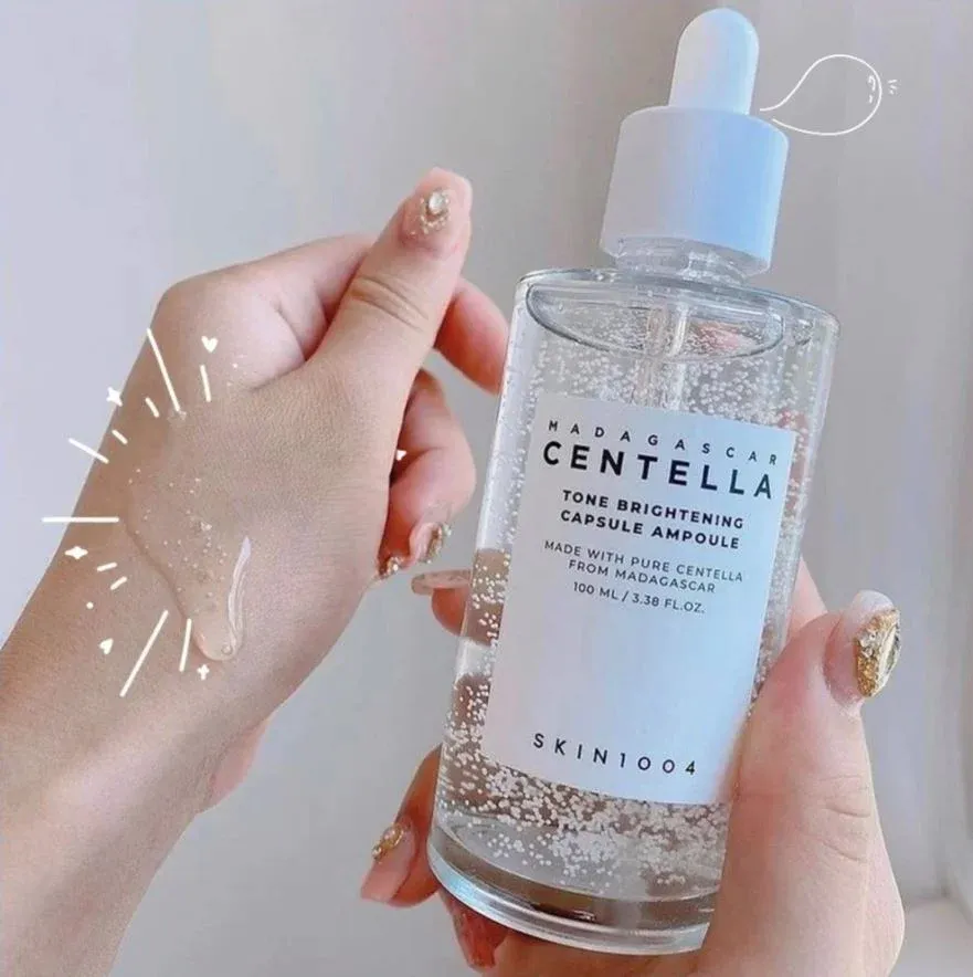Hand holding a clear dropper bottle of Centella skincare serum with a blue cap.