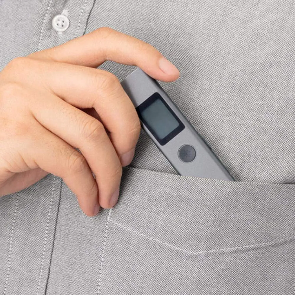 Hand placing a small electronic device with a screen into a shirt pocket.