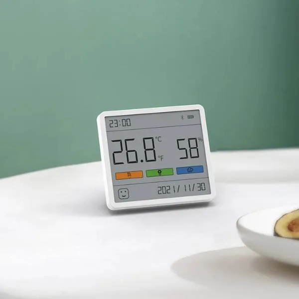 Digital thermometer and hygrometer displaying temperature and humidity on a white table.