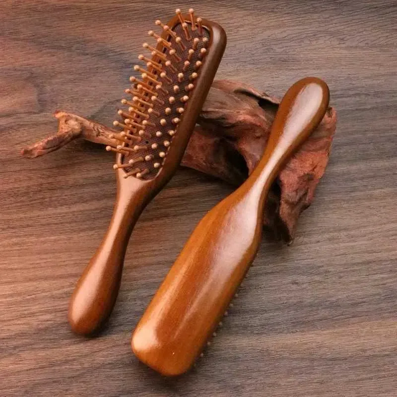Two wooden hairbrushes with rounded bristles on a wooden surface.