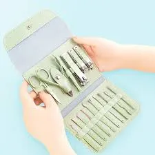 Hands holding an open manicure set with scissors, clippers, and grooming tools in a case.